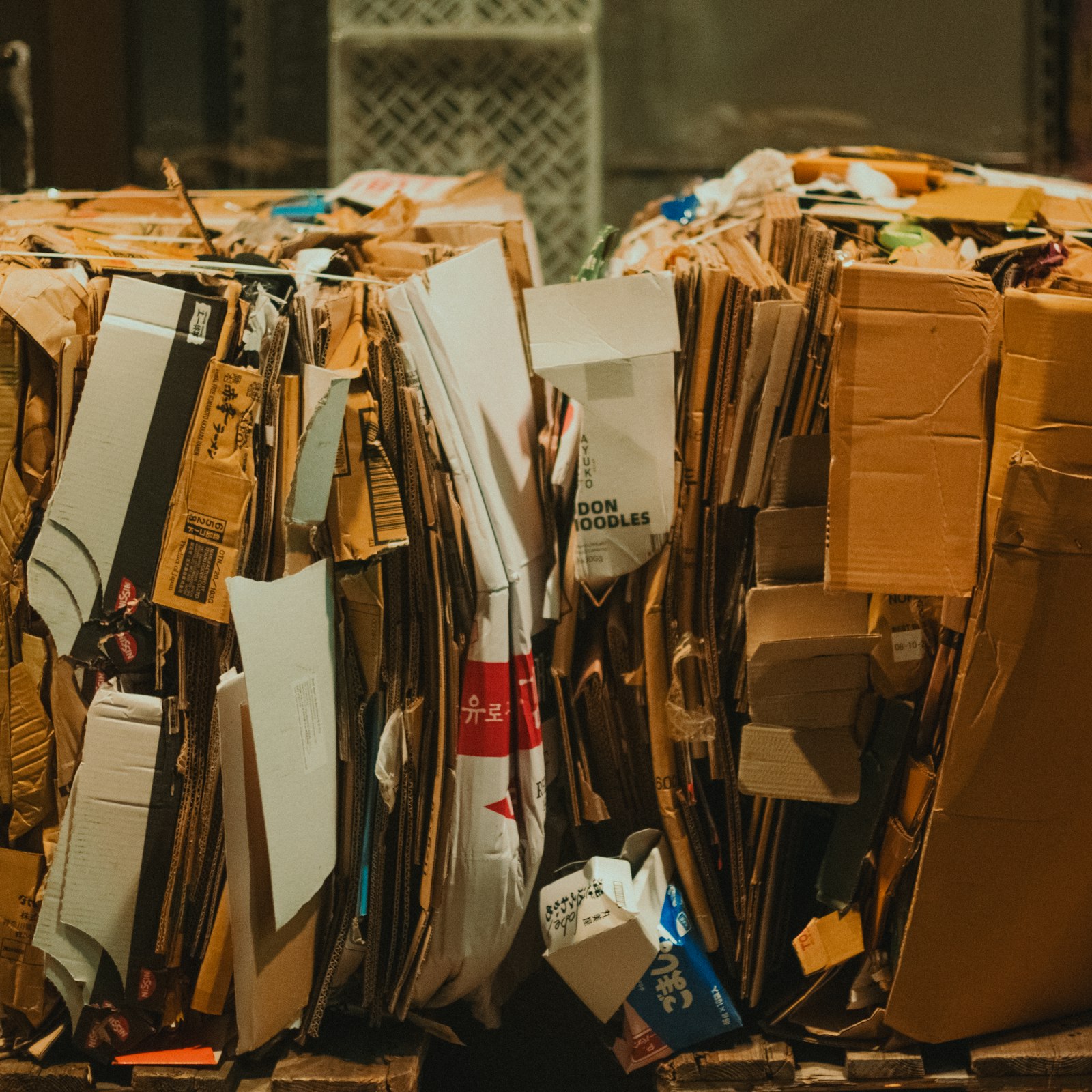 Flattened cardboard sorted into stacks on a wooden floor (illustrative photograph)
